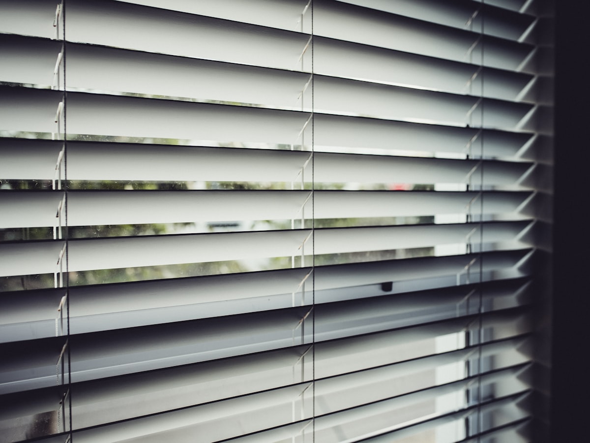Slim micro Venetian blinds tilted across a bright window