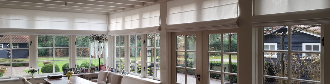 White roman blinds folded across sunroom windows