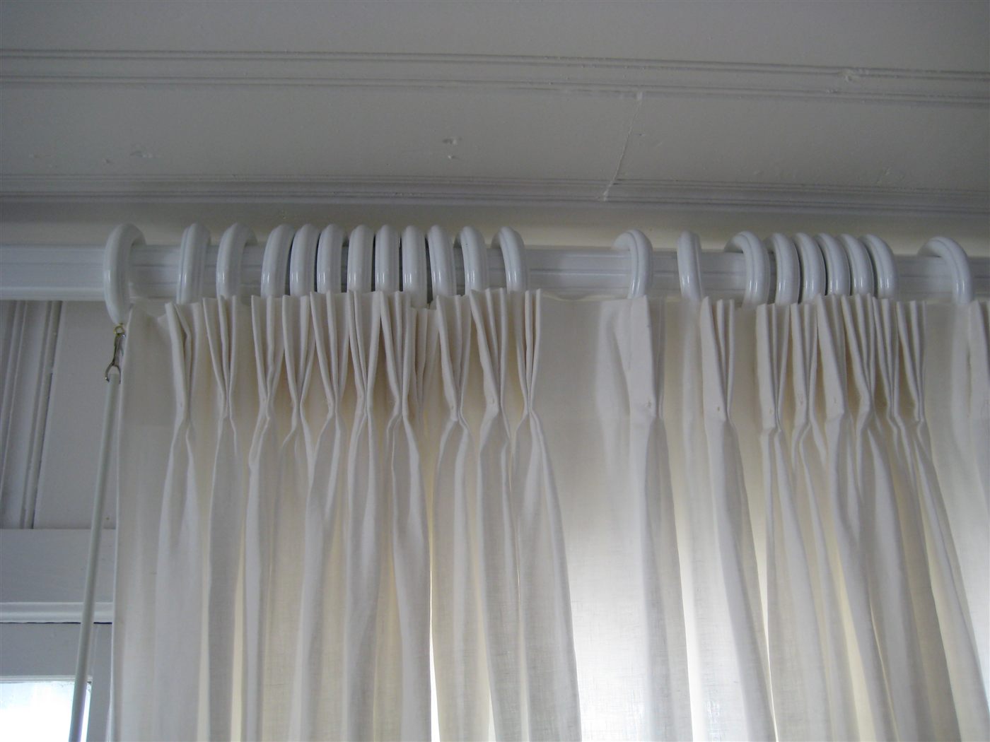 White curtain rod with rings and pinch-pleat drapery hardware